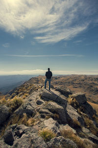 Rear view of man standing on mountain against sky