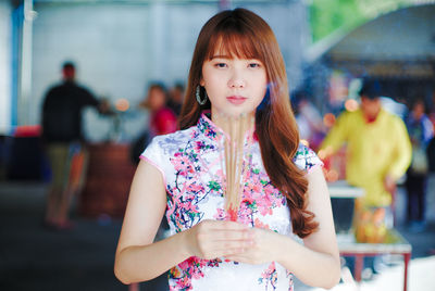 Portrait of beautiful woman with incenses standing at temple