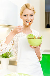 Portrait of young woman eating food at home