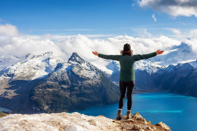 Rear view of man standing on mountain against sky