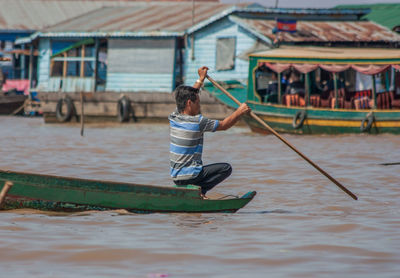 Rear view of man holding boat in water