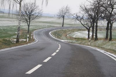 Road amidst bare trees against sky