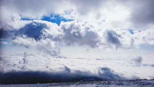 Snow covered landscape against cloudy sky