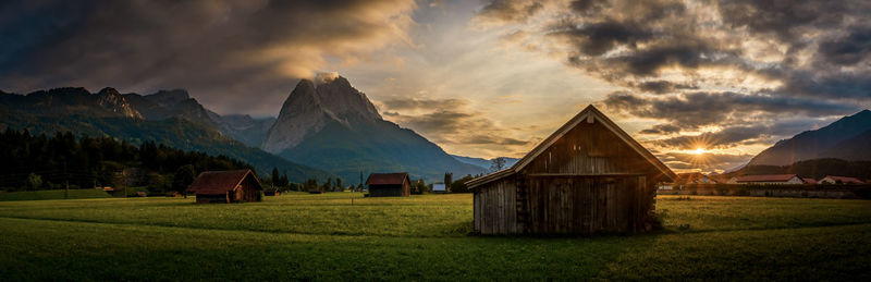 Scenic view of field and houses against sky during sunset