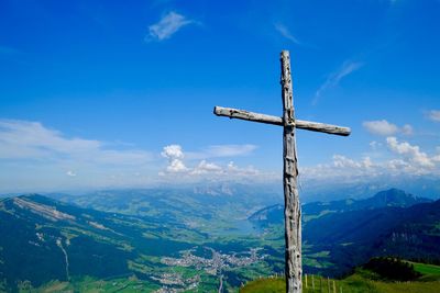 Religious wooden cross on landscape against sky