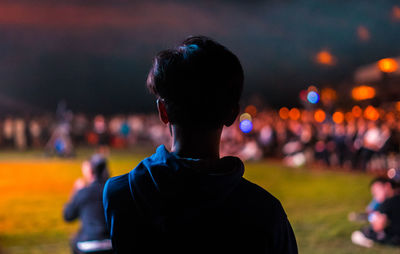 Rear view of man and woman standing at music concert