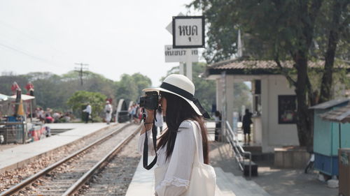 Rear view of woman on railroad tracks against clear sky