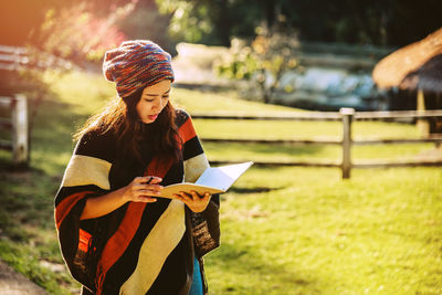 Woman with book and pen standing on land