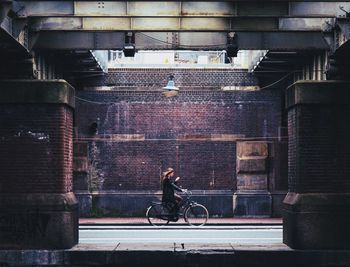 Man riding bicycle on street against building in city
