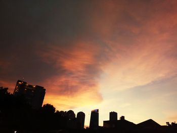 Low angle view of skyscrapers against cloudy sky