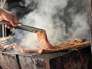 Cropped image of man preparing meat on barbecue grill