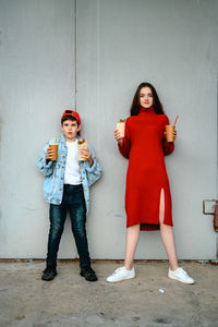 Girl in a red dress and a boy in a denim jacket are holding shawarma and a glass of coffee 