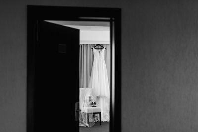 Wedding gown hanging by curtain on wall