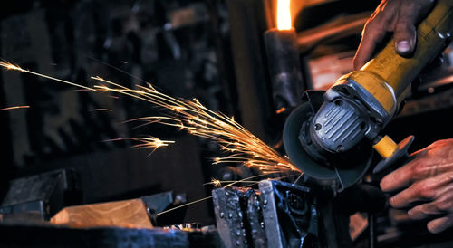 Cropped hands of male worker cutting metal in workshop