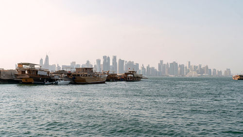 Scenic view of sea and doha skyline against clear sky