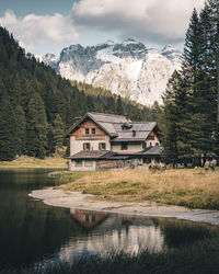 House by lake and mountains against sky