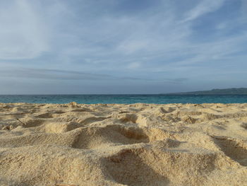 Scenic view of beach against cloudy sky