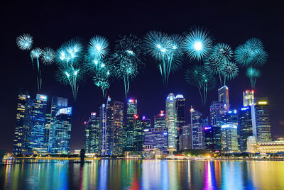 Firework display over illuminated buildings in city at night