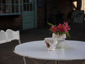 Flower vase by cup on table