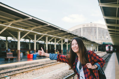 Portrait of smiling young woman standing on railroad station platform