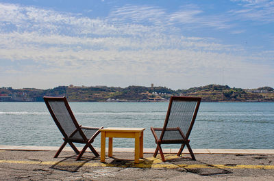 Deck chairs on beach against sky