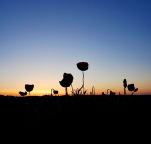 Silhouette birds on land against sky during sunset