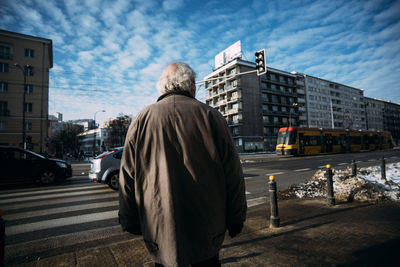 Rear view of man on street against sky in city