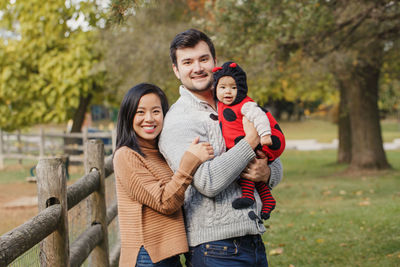 Portrait of happy parents with cute daughter in park