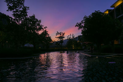Scenic view of swimming pool by lake against sky during sunset