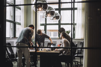 Young businessman discussing over laptop with male and female colleague in meeting room