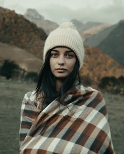 Portrait of beautiful woman standing against mountain during winter