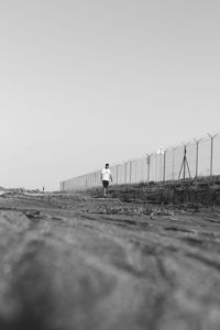 Surface level of man standing on field against clear sky