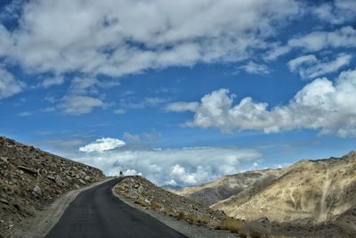 Scenic view of road by mountains against sky