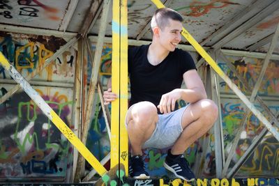 Young man sitting on built structure 