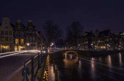 Illuminated bridge over river at night