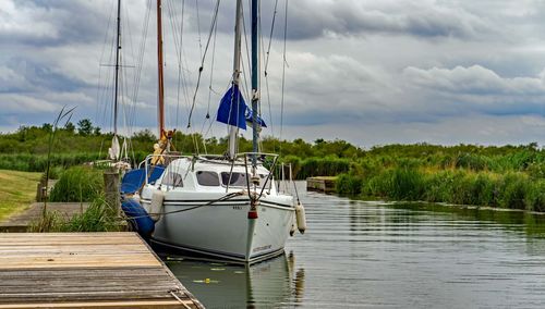 Sailboats moored on lake against sky