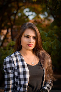 Portrait of young woman standing against plants