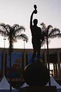 Low angle view of statue in front of building against clear sky