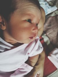 Close-up of baby girl lying on bed