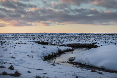 Scenic view of snow covered land against sky during sunset