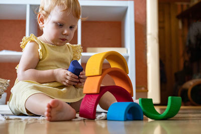 Boy looking away while sitting on floor at home