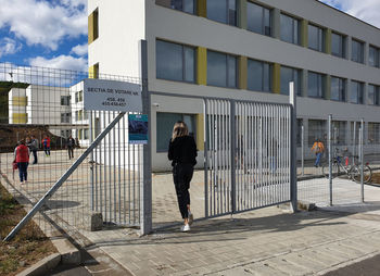 Full length of woman walking on footpath against buildings in city