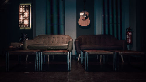 Empty sofas and tables against guitar on wall