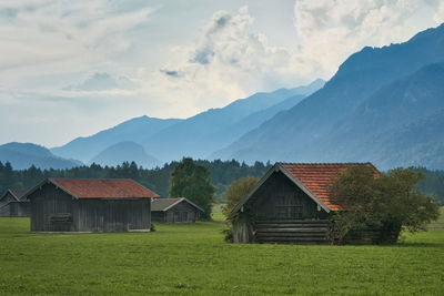 House on field by mountains against sky