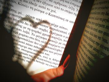 Close-up of cropped hand writing on book