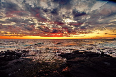 Scenic view of sea against dramatic sky during sunset