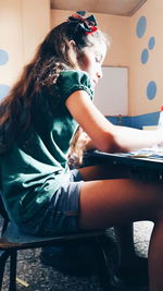 Side view of girl doing homework while sitting at home