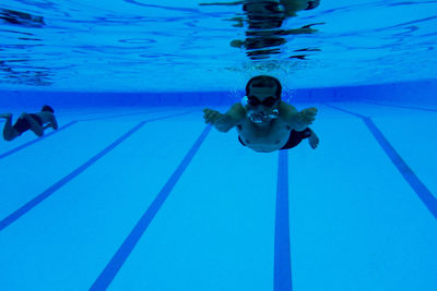 Shirtless man swimming in pool