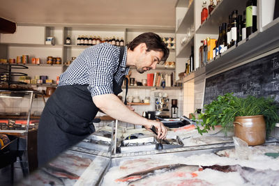 Side view of owner looking at fishes in store