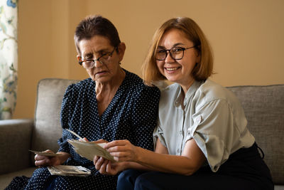 Mature daughter visits senior mother and watching family photo album